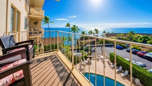 Un balcon avec piscine, donnant sur un parking et une plage.