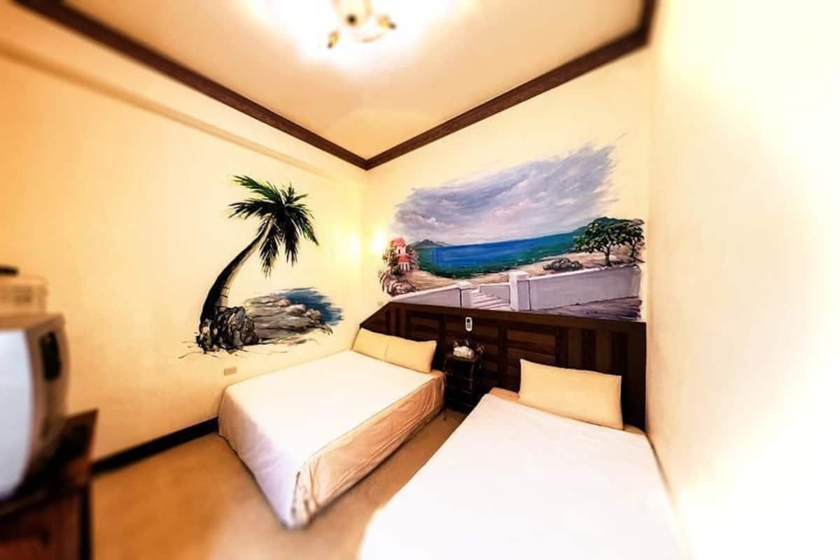 A hotel room with two beds, a television, and a mural of a beach scene.