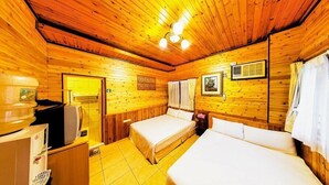 Ein Holzblockhaus-Zimmer mit zwei Betten, einer Küchenzeile und einer Deckenleuchte.