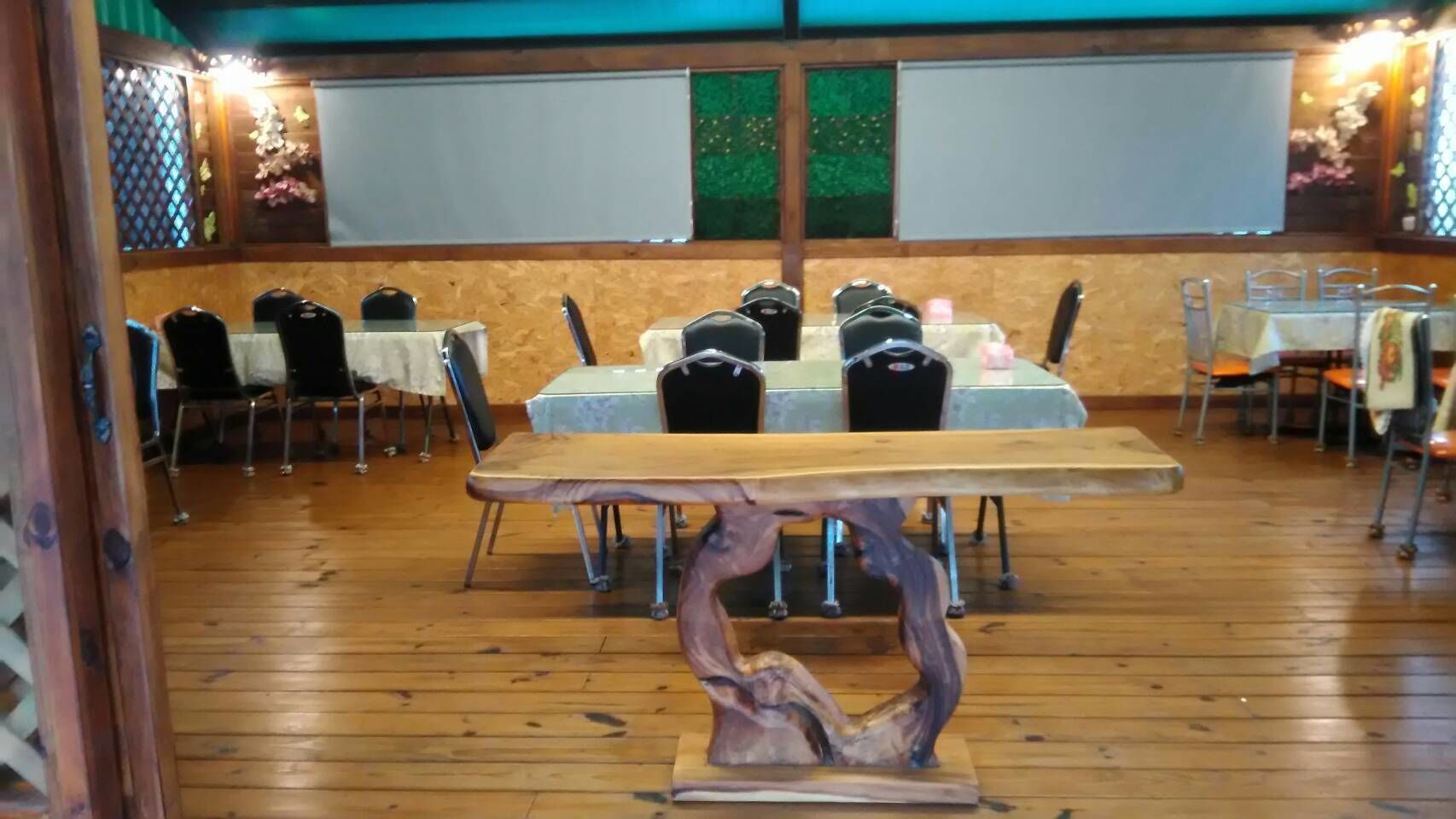 Un salón de conferencias con una mesa y sillas de madera, una pizarra y una ventana con vistas a zonas verdes.