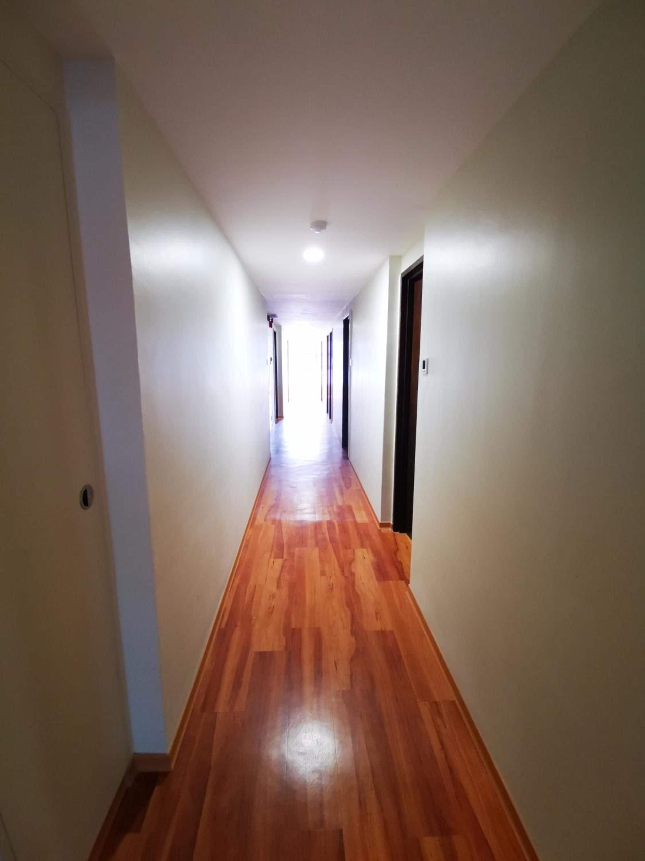 A long, narrow hallway with wooden flooring and white walls.