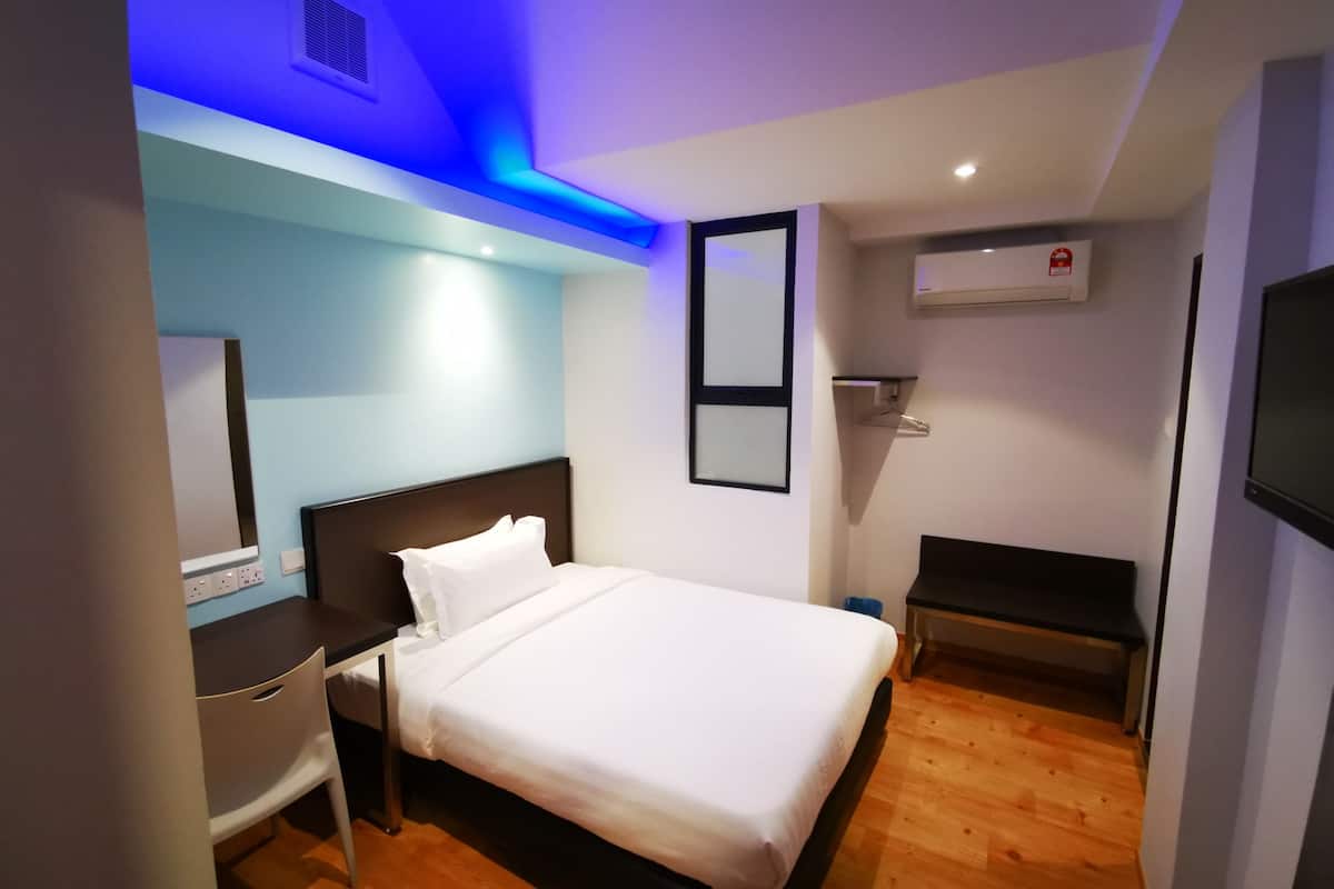 A modern hotel room with a neatly made bed, a desk, and a TV.