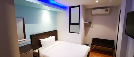 Una habitación de hotel moderna con una cama bien hecha, un escritorio y un televisor.