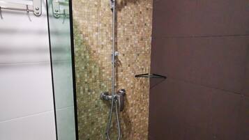 Un baño con ducha, inodoro y mampara de vidrio.