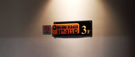 A wall-mounted sign with phone numbers and a no-smoking symbol.