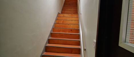 A staircase with wooden steps and metal handrails, leading to a landing with a light fixture.
