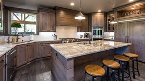 Una cocina amplia con armarios de madera, una isla grande con taburetes, horno empotrado y ventana con vistas.