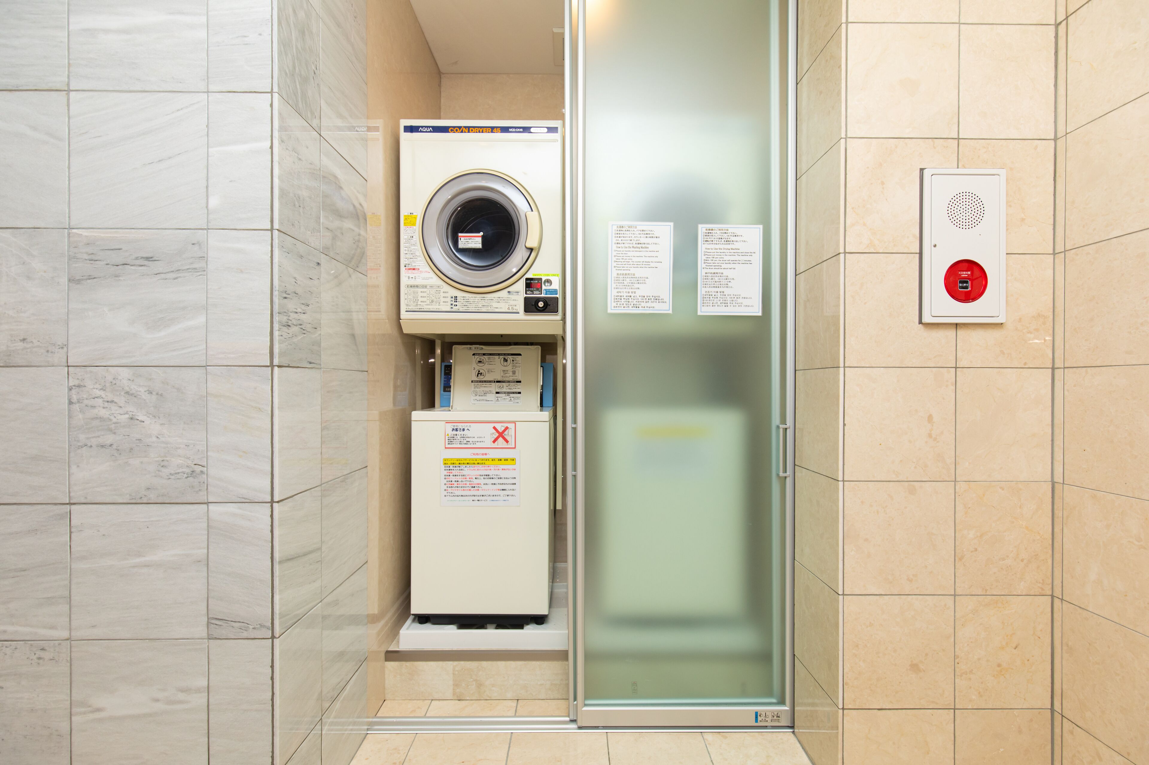 A compact laundry room with a washing machine, dryer, and a glass door.