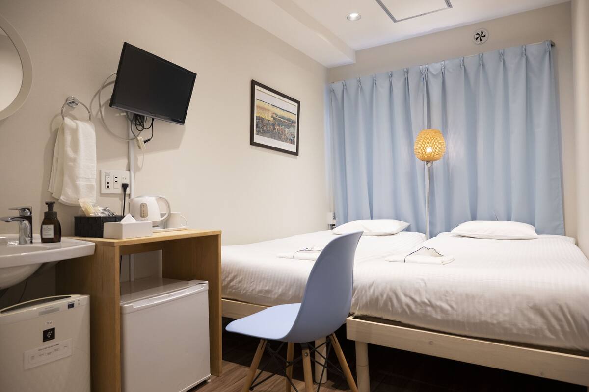 Une chambre d’hôtel comprenant un lit, un bureau avec une chaise, un lavabo et un téléviseur.