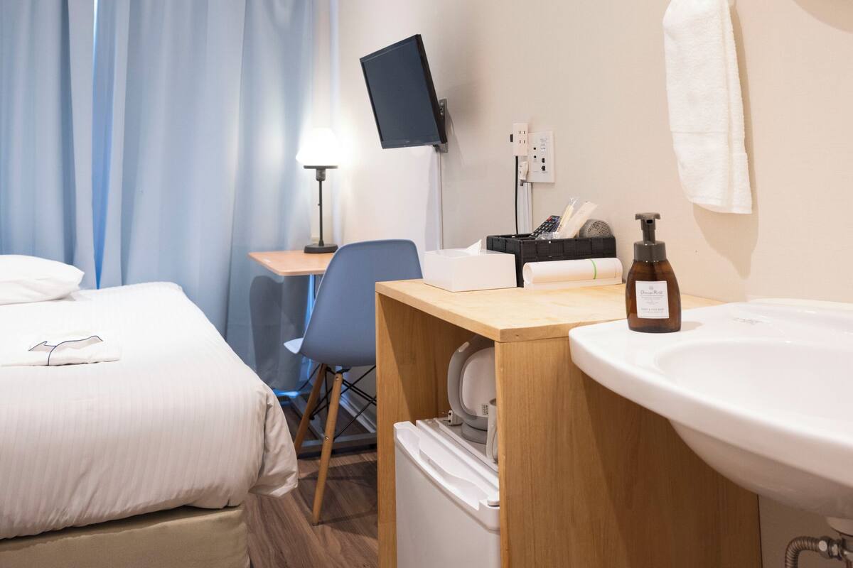 Une chambre d’hôtel équipée d’un lit, d’un bureau, d’une chaise, d’une télévision et d’une salle de bain avec un lavabo et un miroir.