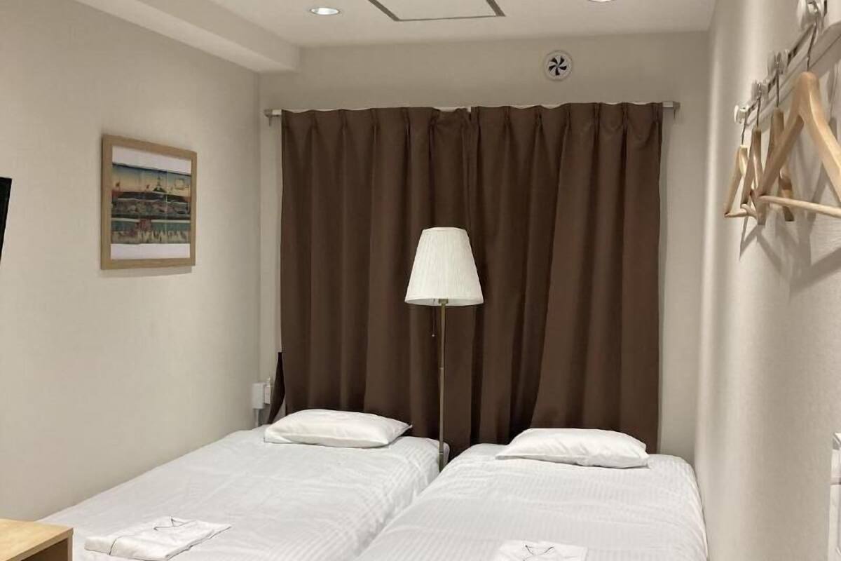 Une chambre d’hôtel avec deux lits, un bureau, une chaise, une lampe et un tableau au mur.