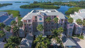 A multi-story hotel with a central courtyard, surrounded by palm trees and a view of a waterway with islands.