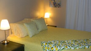 A neatly made bed with a yellow bedspread and pillows, two bedside lamps, and a painting on the wall. - Cripple Creek Beauty  (Cripple Creek)
