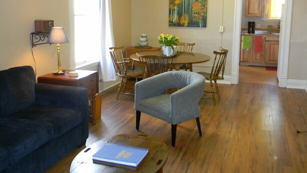 A living room with a sofa, a dining table with chairs, a lamp, and a painting on the wall. - Cripple Creek Beauty  (Cripple Creek)