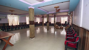 Un vaste hall doté de rangées de chaises rouges, de piliers en bois et de ventilateurs de plafond.