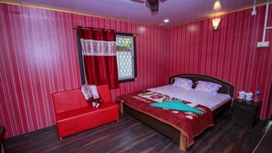 Une chambre à coucher avec un lit, un canapé rouge, une table de chevet et un ventilateur de plafond.