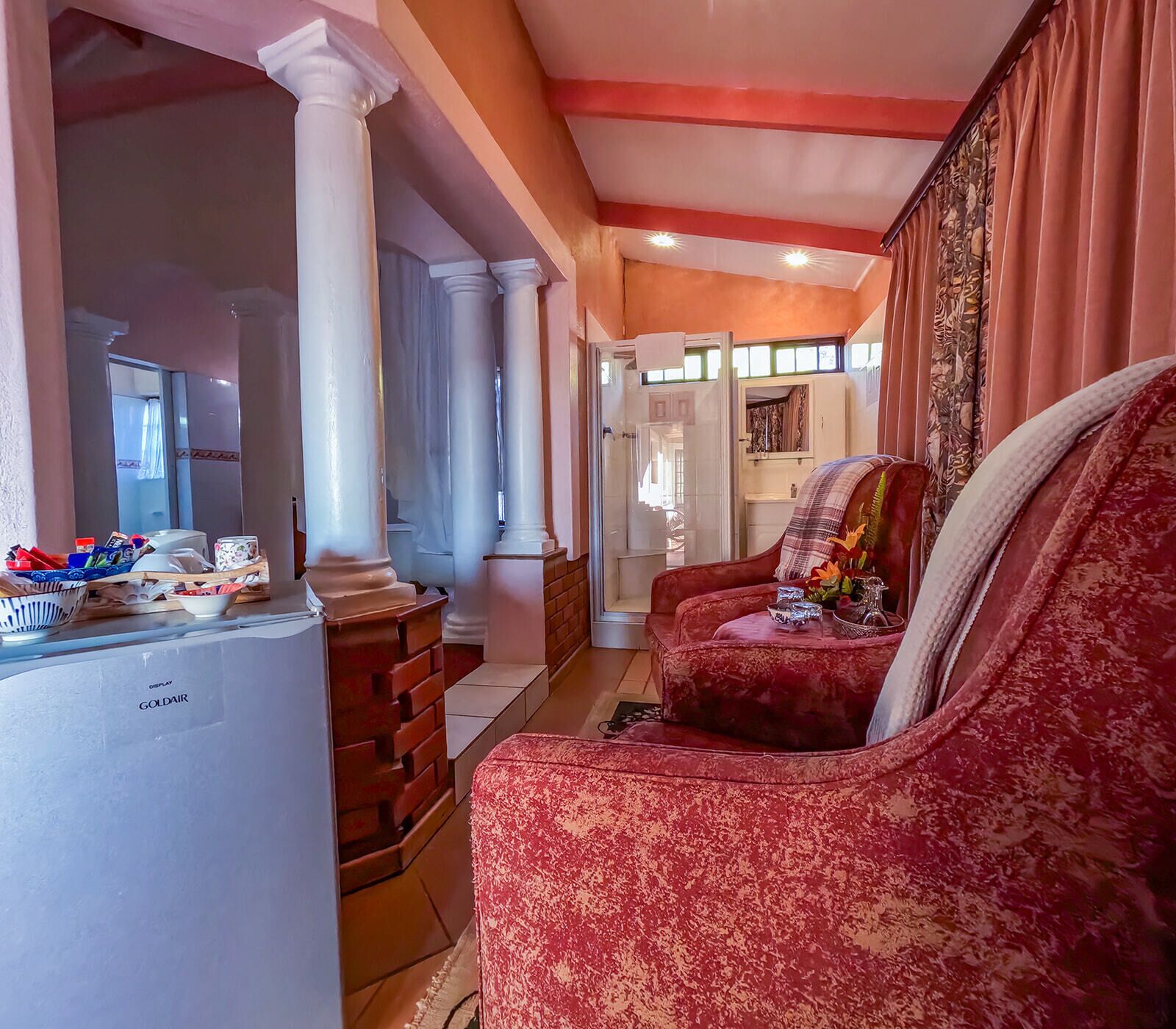 A cozy living room with a red sofa, a white refrigerator, and a brick wall.