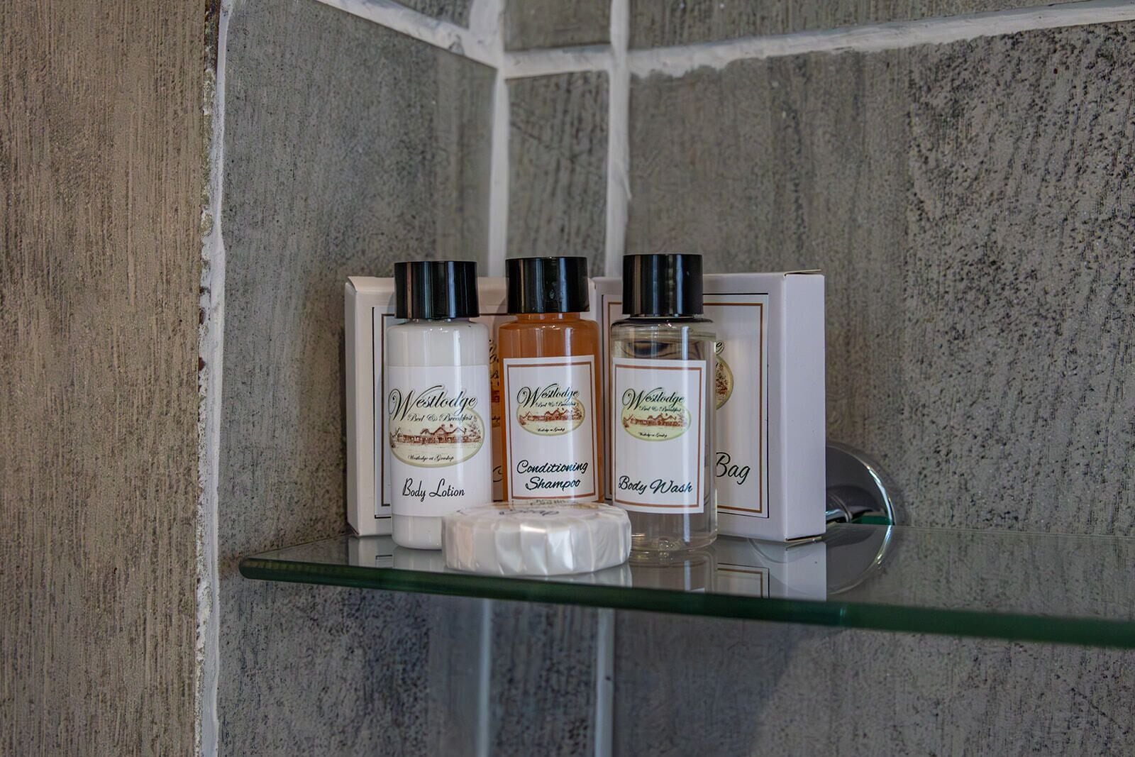 A bathroom shelf with West Lodge body care products including lotion, shampoo, and body wash.