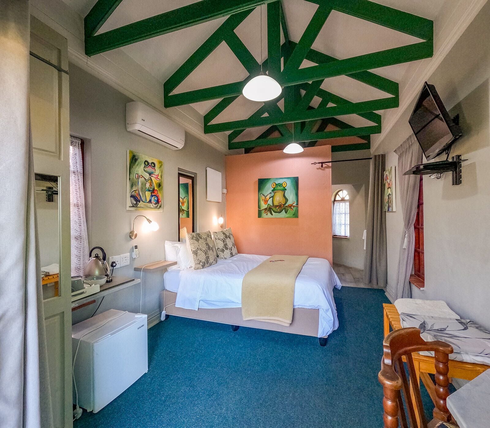Une chambre à coucher comprenant un lit, des tables de chevet, un bureau, une chaise et un téléviseur.