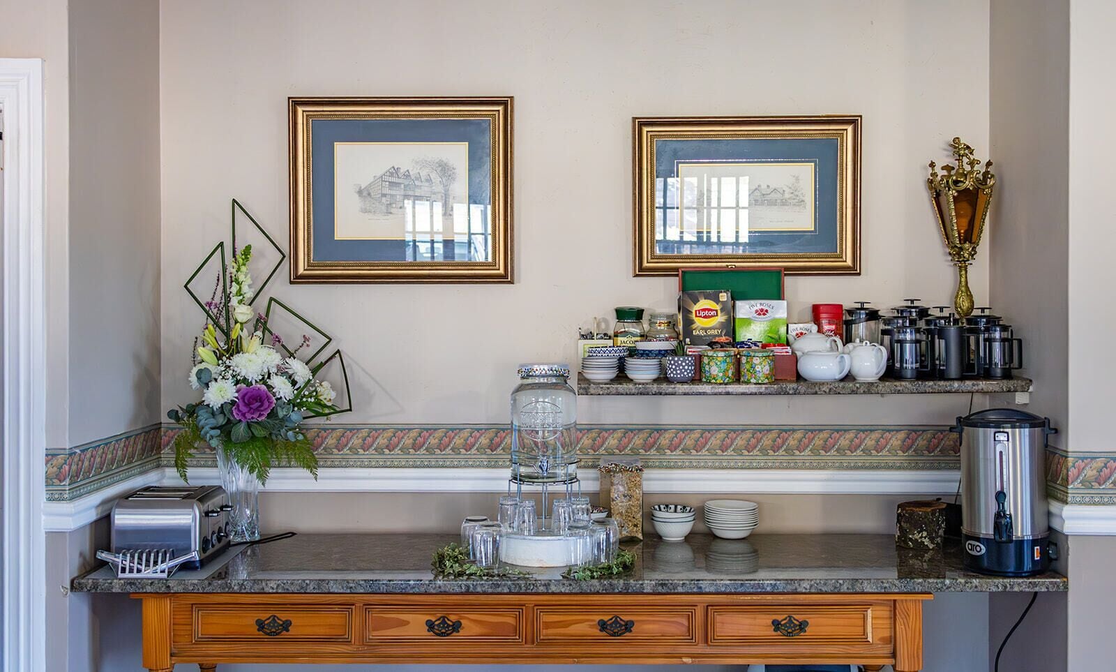 Eine Küche mit Granitarbeitsplatte, einem Toaster, einer Blumenvase, einer Kaffeemaschine und gerahmten Bildern an der Wand.