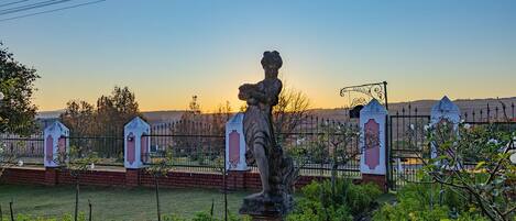 A garden with a statue, a fence, and a gate.