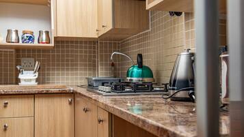 A kitchen with wooden cabinets, a gas stove, a kettle, and a coffee maker.