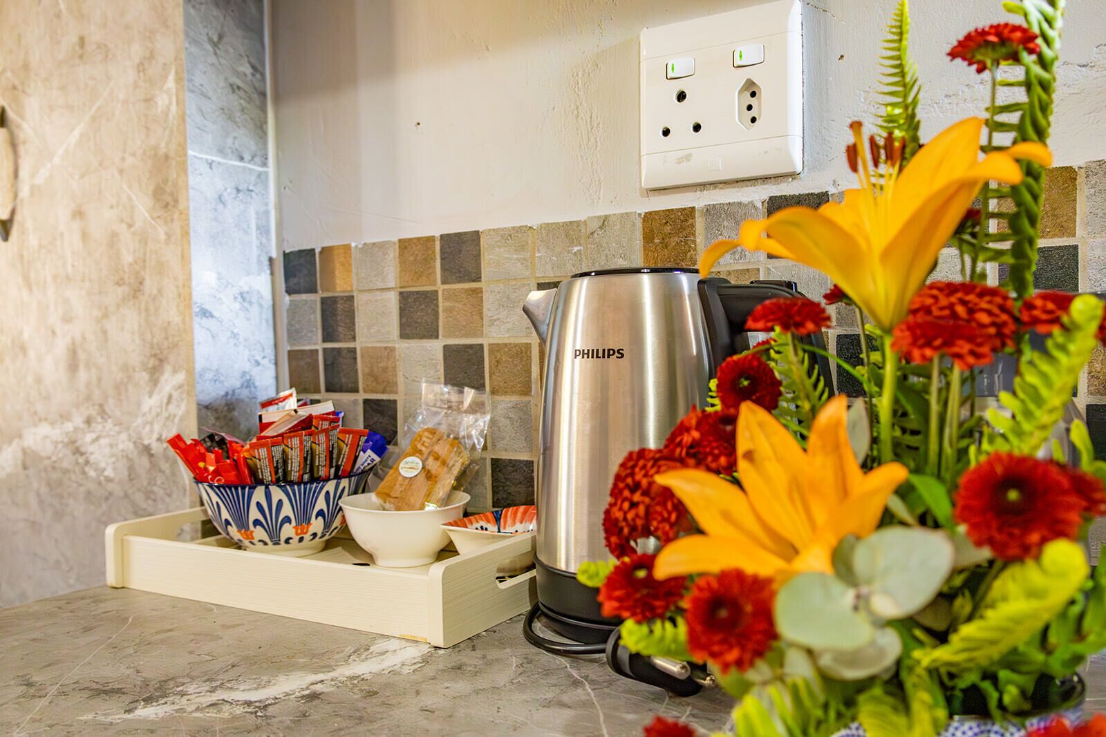 Eine Küchenarbeitsplatte mit Kaffeemaschine, einer Schale mit Snacks und einer Blumenvase.