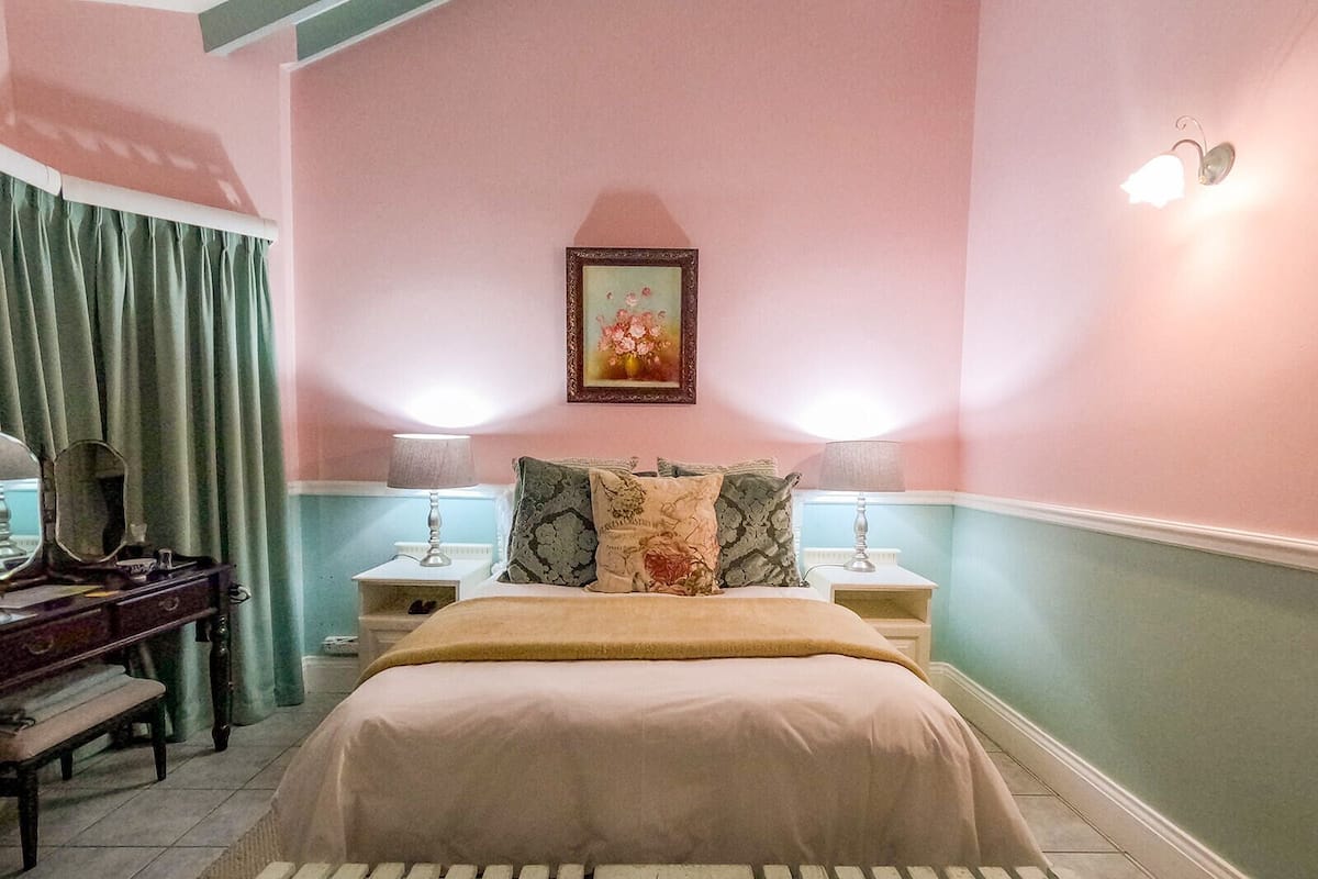 A bedroom with a bed, two bedside tables, a dresser, a mirror, and a picture on the wall.