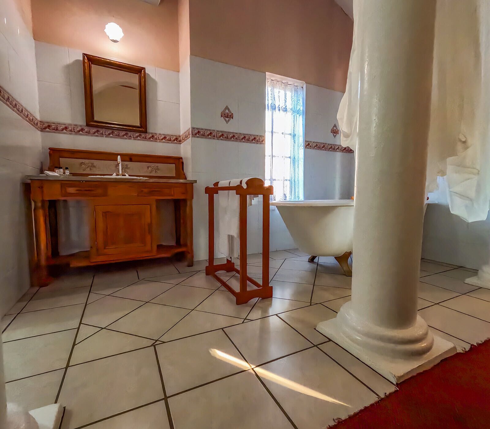 A bathroom with a wooden vanity, a bathtub, and a large mirror.