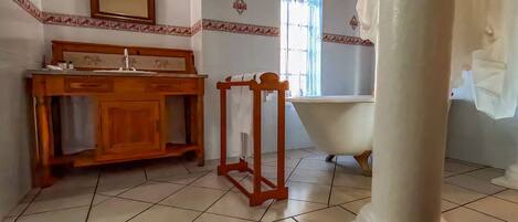 A bathroom with a wooden vanity, a bathtub, and a large mirror.
