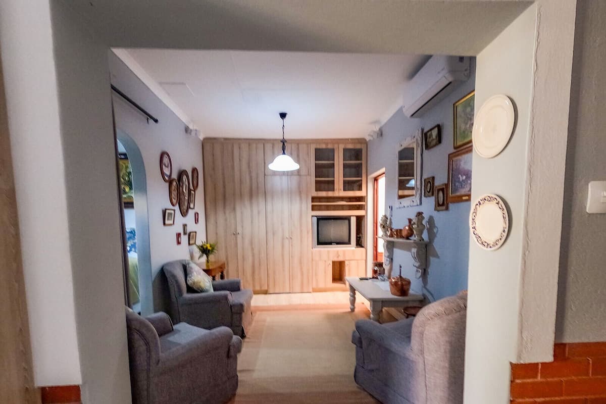 A living room with two sofas, a coffee table, and a TV. There are wooden cabinets and a hanging light fixture.