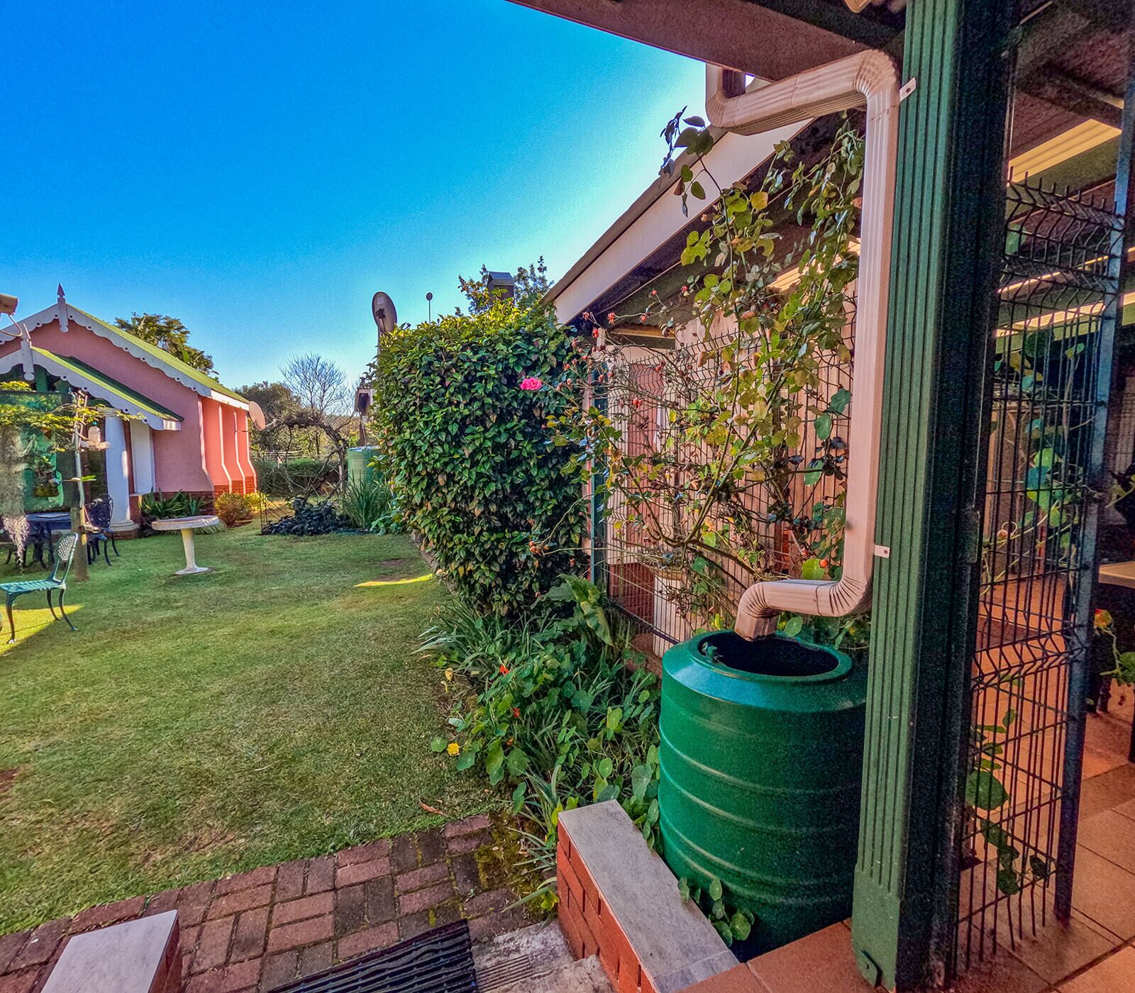 A residential backyard with a green barrel, a brick wall, and a metal fence.
