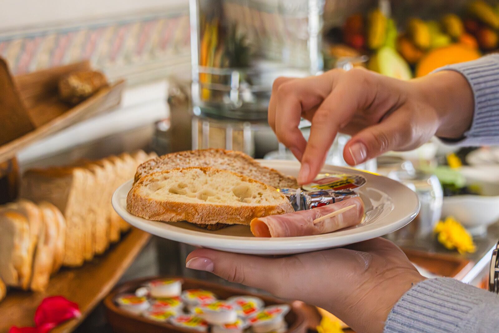 Uma pessoa segurando um prato com fatias de pão e um pedaço de carne.