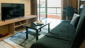 Un salon équipé d’un téléviseur à écran plat, d’un canapé, d’une table basse et d’un coin repas avec une chaise.