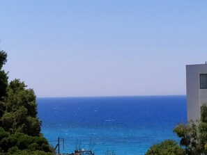 A coastal view with a clear sky, a body of water, and a modern building with a window.