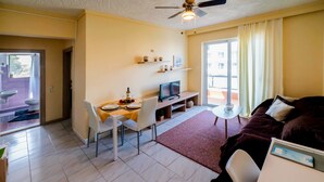 Un espace de vie compact comprenant un coin repas, un téléviseur, un canapé et un balcon avec vue.