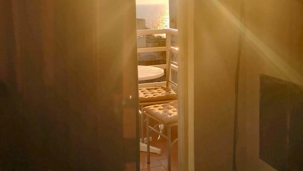Une pièce avec vue sur la mer, visible par une fenêtre, comprenant une table ronde et un lampadaire.