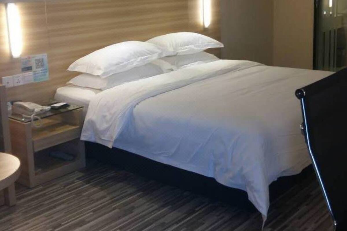 A hotel room with a bed, bedside table, and a lamp.
