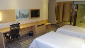 Ein Hotelzimmer mit Schreibtisch, zwei Betten, Fernseher und Spiegel.