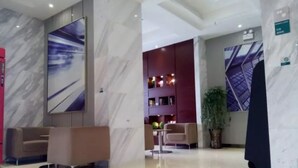 Eine moderne Lobby mit Marmorwänden, einer Sitzecke mit Sofas, einem Bücherregal und einer Zimmerpflanze.