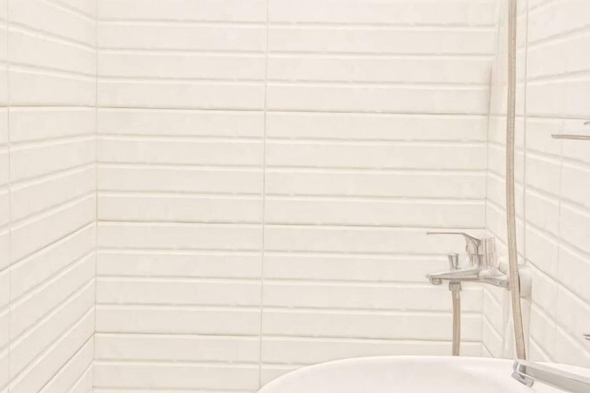 A bathroom with white tiled walls and a white sink.
