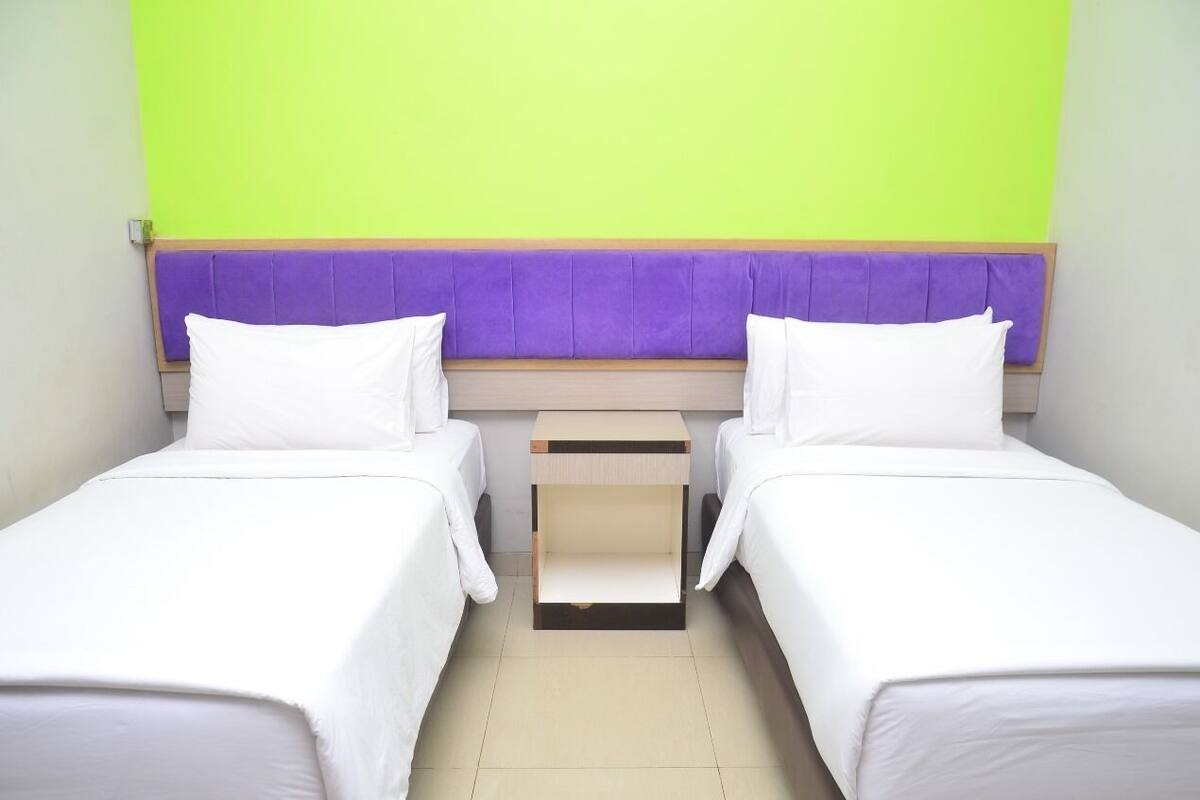 A twin room with two beds, a wooden nightstand, and a purple headboard.