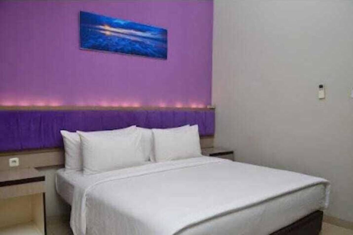 A hotel room with a bed, a nightstand, and a wall-mounted painting.