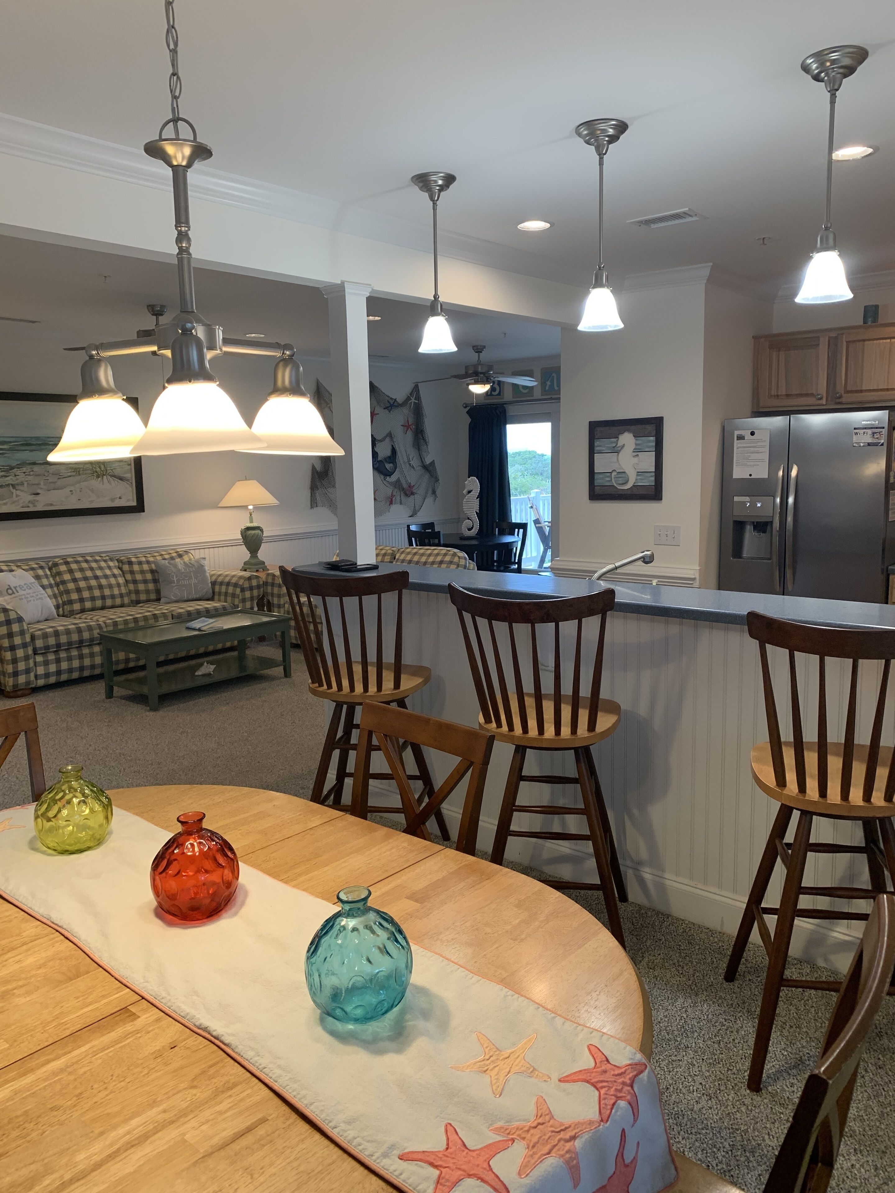 Una cocina moderna con una isla central, sillas de madera e iluminación colgante.