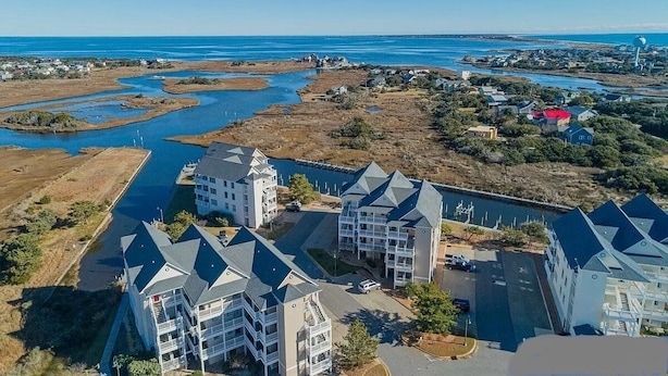 A coastal hotel with multiple buildings, including a prominent tower and several smaller structures. - SeaToo Waterfront Condo (Hatteras)