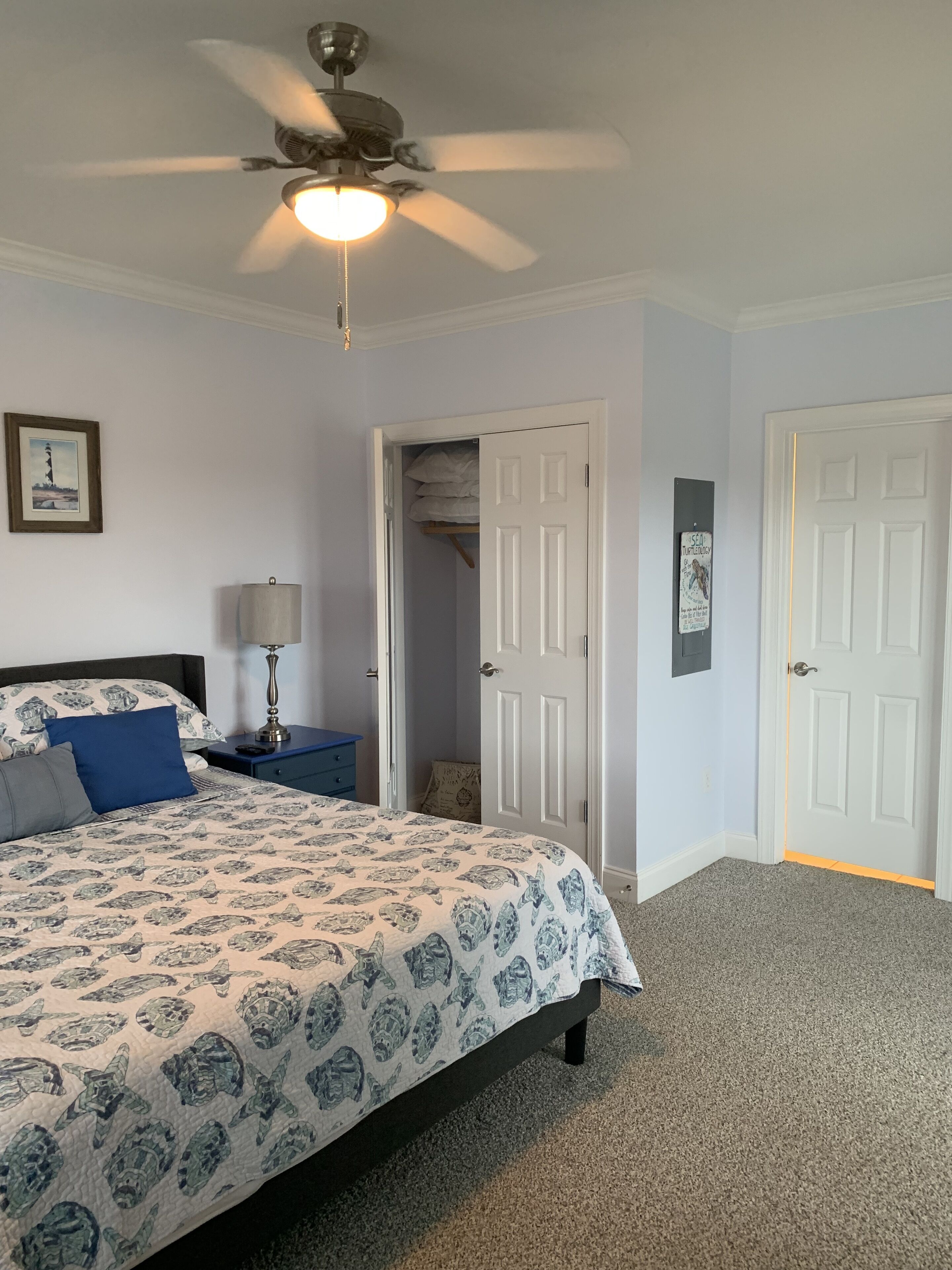 A bedroom with a bed, a ceiling fan, a nightstand, a lamp, and a door to a closet.