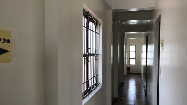 A corridor with a barred window, a door with a number sign, and a tiled floor. - Van Anh Motel (Hai Phong)