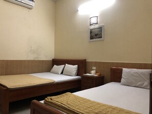 A hotel room with two single beds, a wooden headboard, a nightstand with a lamp, and a wall-mounted air conditioner. - Van Anh Motel (Hai Phong)