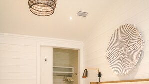 A bedroom with a bed, a hanging light fixture, a wall-mounted lamp, and a large decorative wall piece.