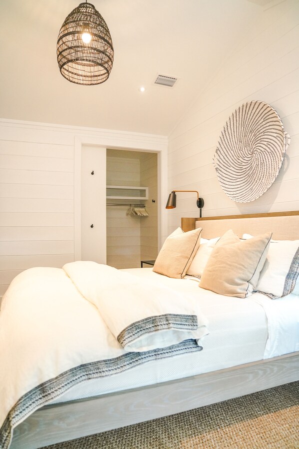Un dormitorio con cama, una lámpara colgante, una lámpara de pared y un elemento decorativo grande en la pared.